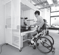 写真：スタンディング車いすを使い、立位で実験装置を使う様子